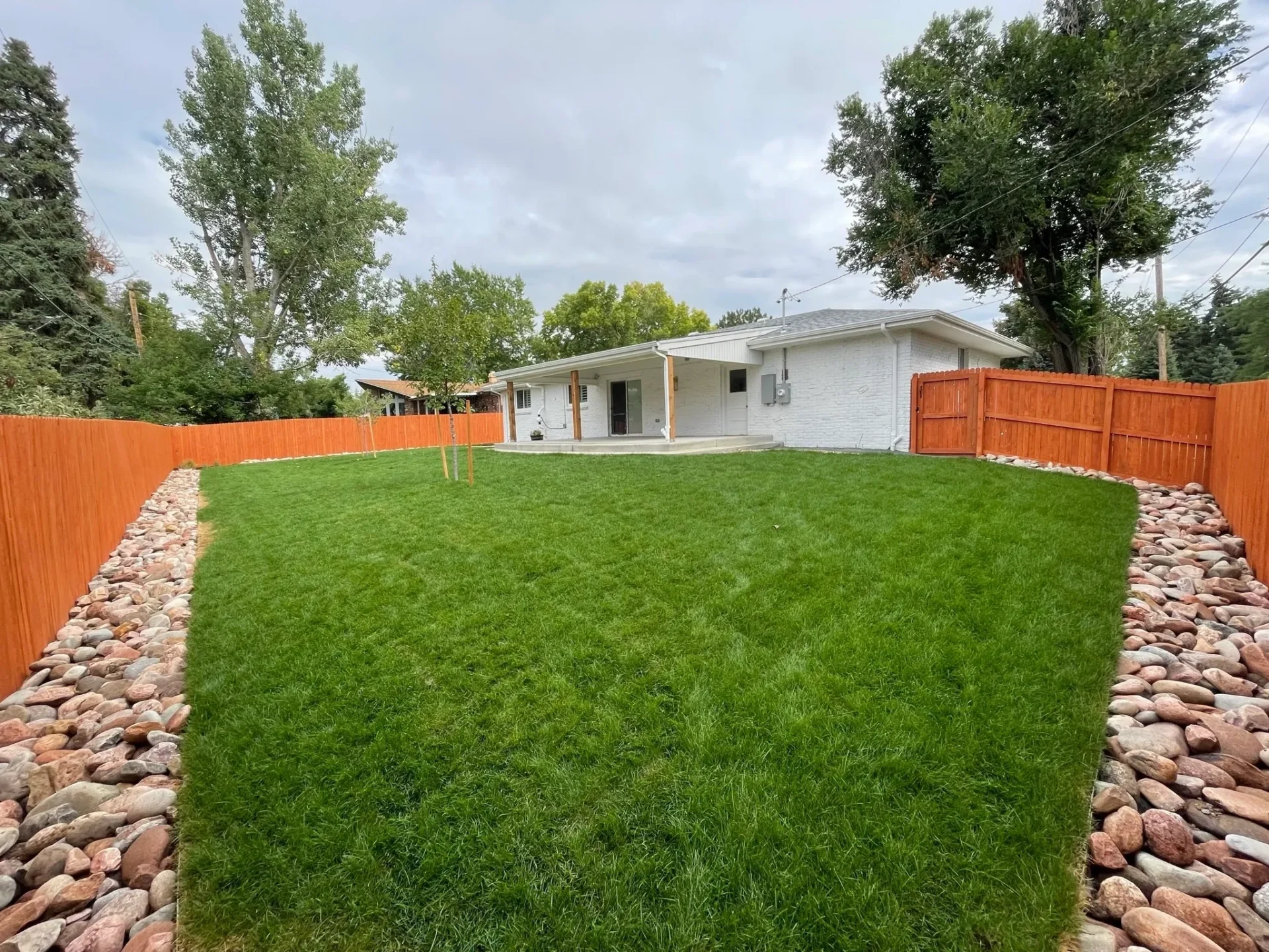 A yard with grass and trees in the background.