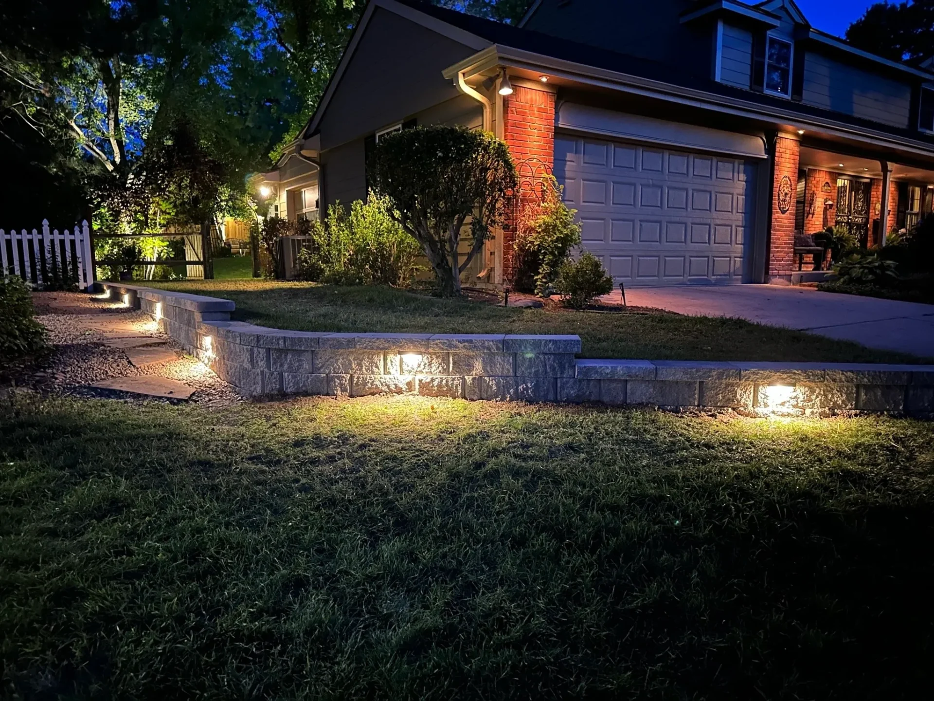 A house with lights on the ground and grass