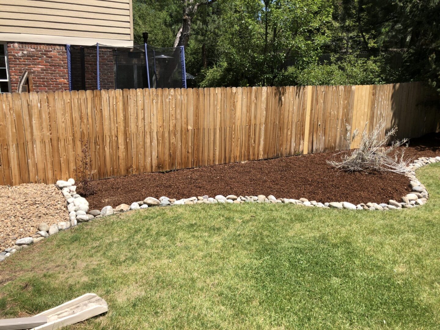 A backyard with grass and rocks in the middle of it.